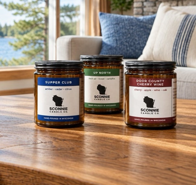 Three Sconnie Candle Co. candles overlooking a Wisconsin lake